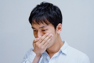 口を押さえる男性