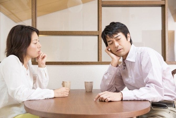 テーブルで話す女性と面倒くさそうな男性