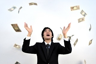 お金を宙に投げているスーツ男性