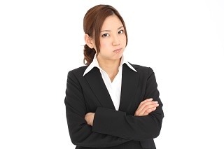 腕を組んで怒っているスーツ女性