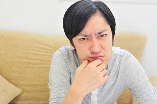あごを押さえてにらんでいる男性