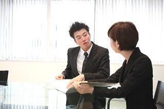 会議室で話すスーツ男女