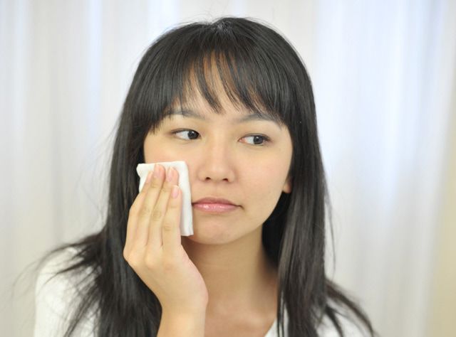 コットンで顔の脂を押さえる女性