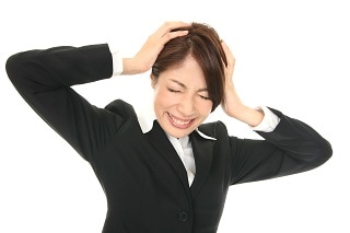 頭を抱えるスーツ女性