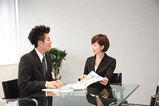 テーブルで説明するスーツ女性
