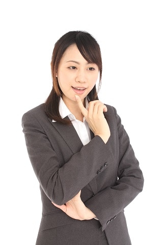 手を口に置いているスーツ女性