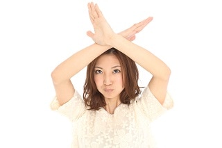 頭の上で×をしている女性