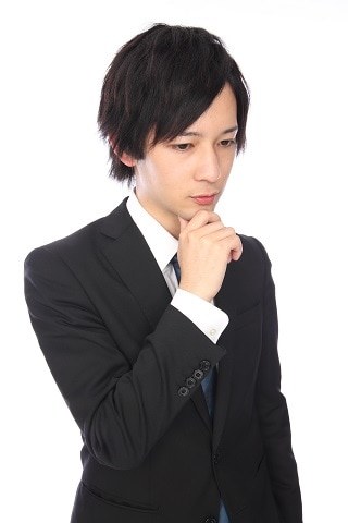 あごを押さえているスーツ男性