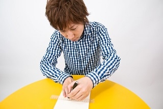 テーブルで何かを書く男性