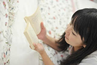 寝転んで本を読む女性