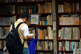 本棚の前で本を読む男性