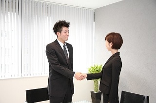 握手をするスーツ男女