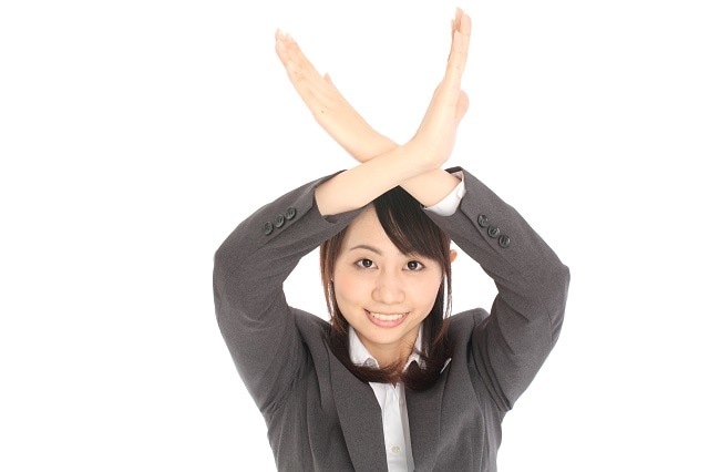 頭で×をしている女性