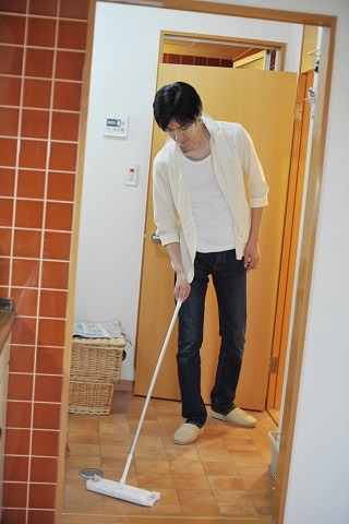 モップで床をきれいにする男性