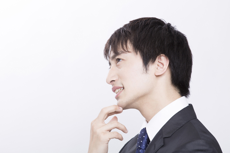 あごに手を置いて考えているスーツ男性