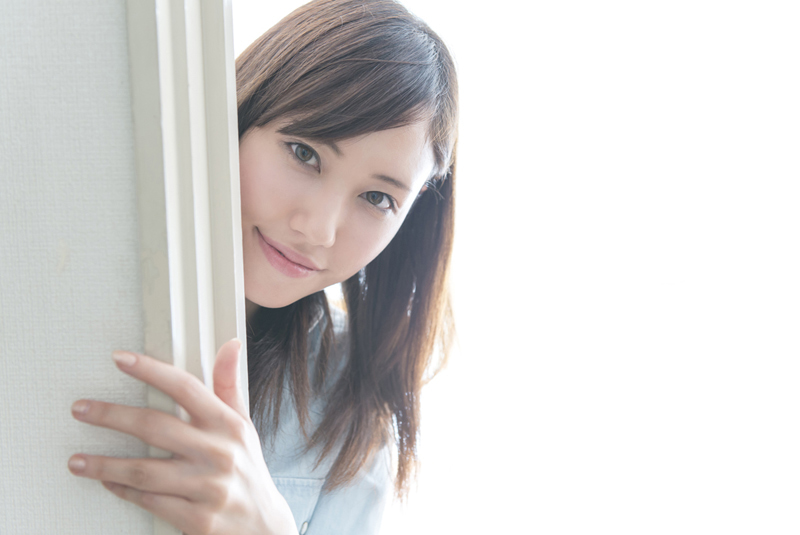 壁の端からのぞいている女性