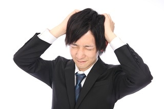 頭を抱えるスーツ男性