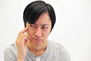 こめかみを押さえる男性
