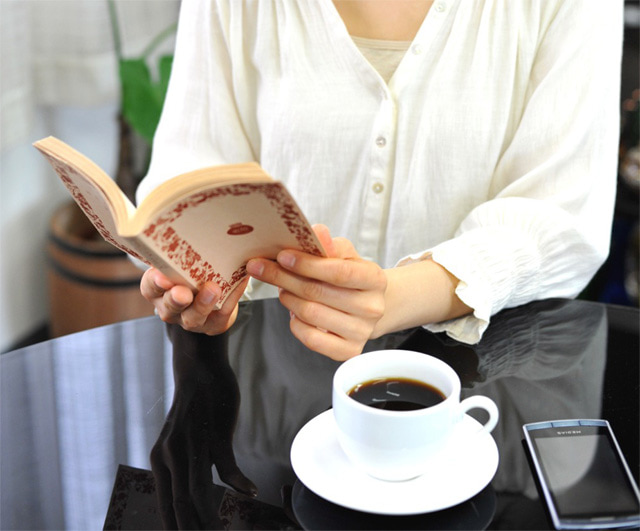 コーヒーを飲みながら本を読む女性