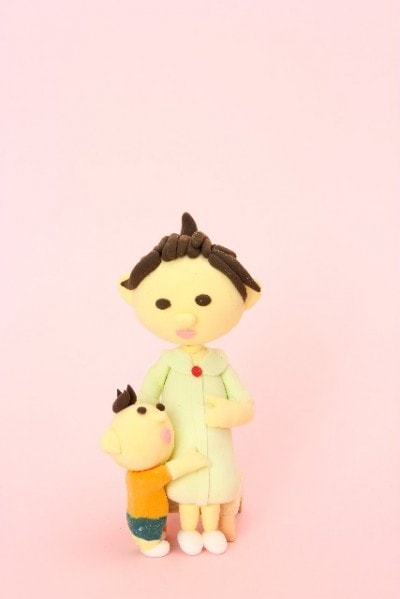 お腹をさすっている妊婦女性と子供の粘土人形