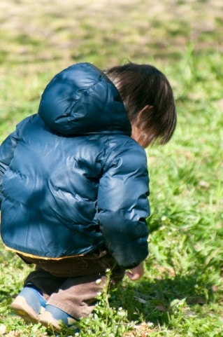 草をいじっている男の子