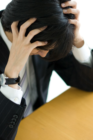頭を抱えるスーツ男性