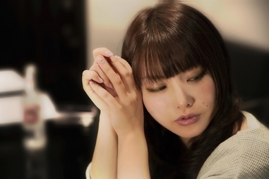 指を組みつつ流し目している女性