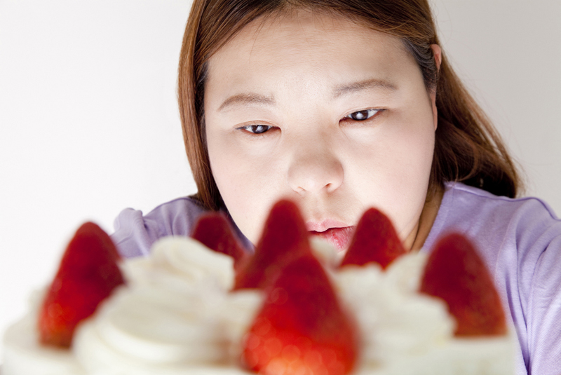 ケーキをじっと見る太った女性