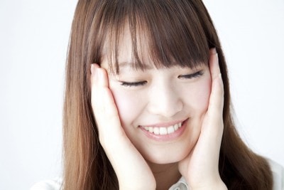 笑いながら両頬を押さえる女性