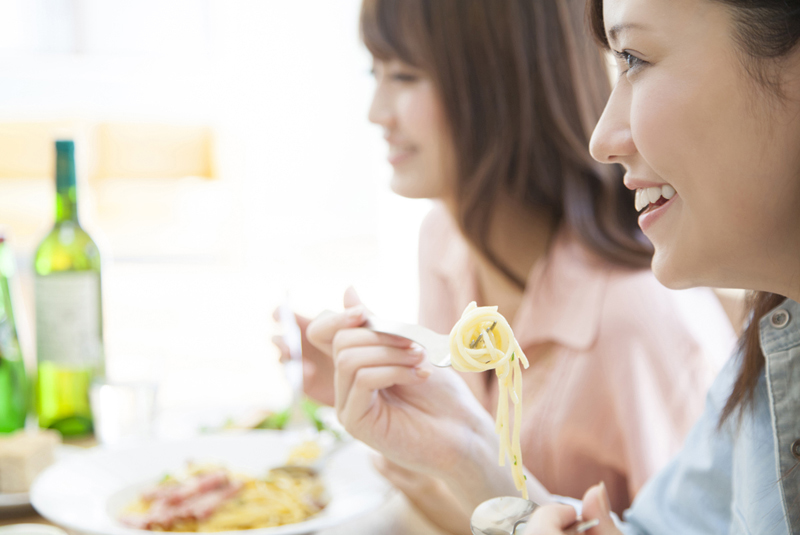 レストランでパスタを食べる女性