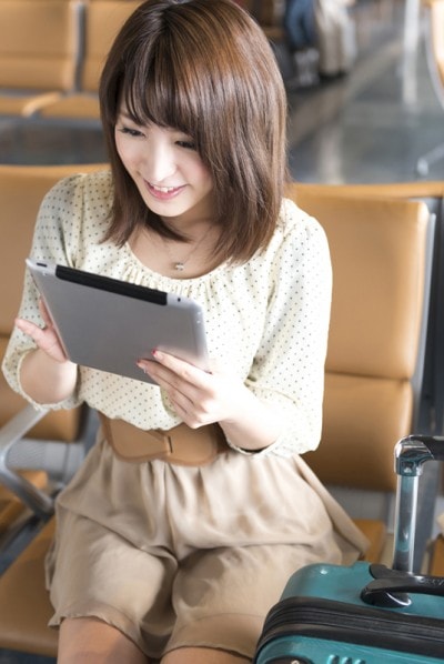 いすに座ってタブレットをしている女性