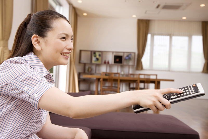 テレビのリモコンを操作している女性