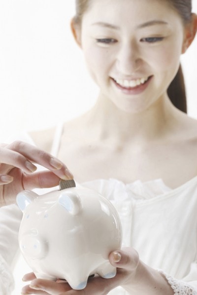 貯金箱に貯金をする女性