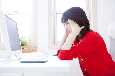 こめかみを押さえる女性