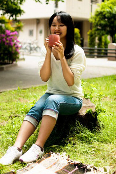 コップを両手で持つ女性