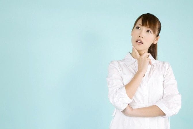 悩んでいる白シャツの女性